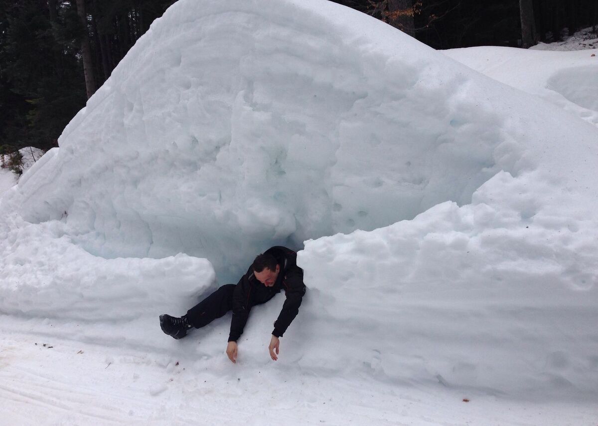 мужчина в большом сугробе снега