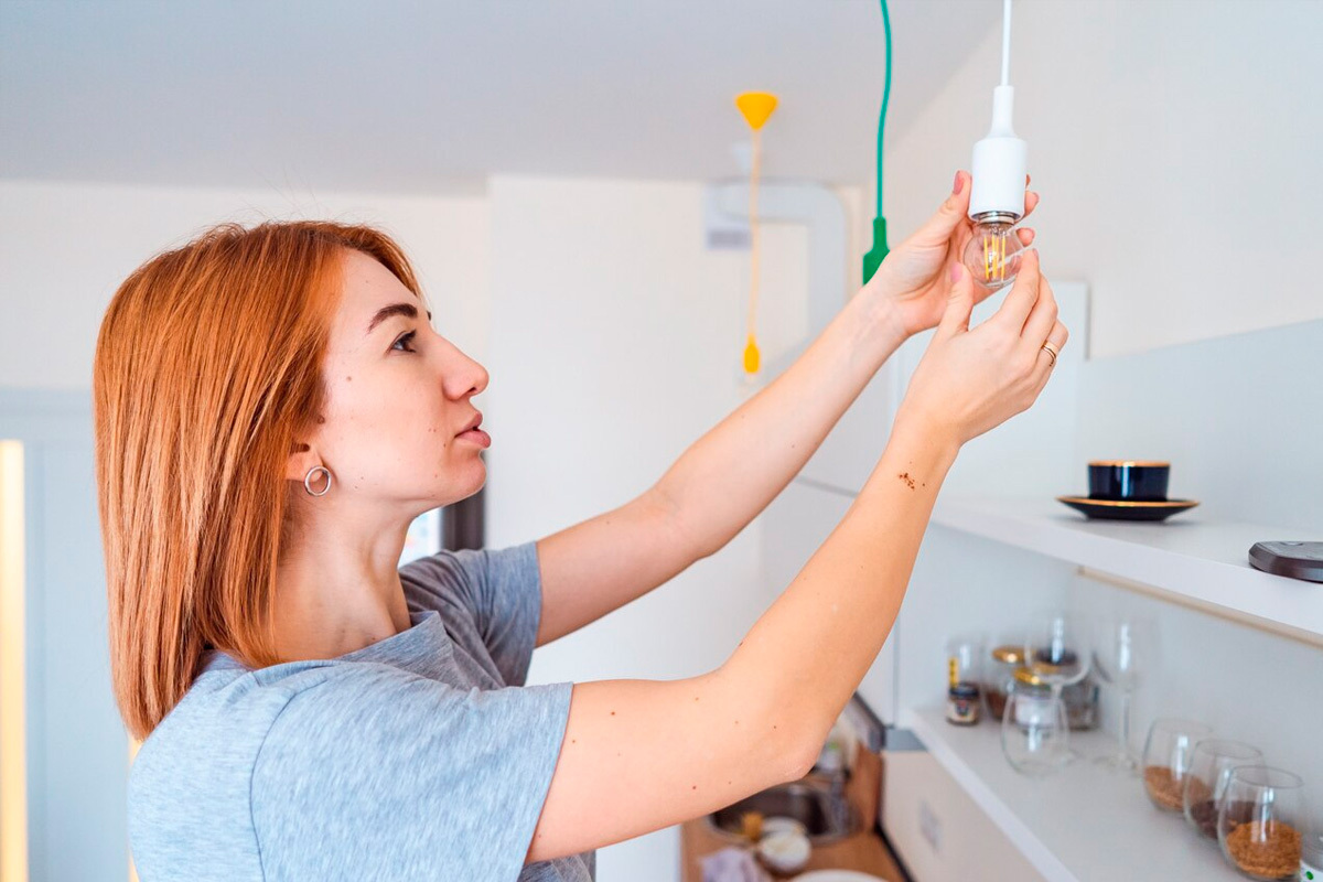 человек вешает лампочку