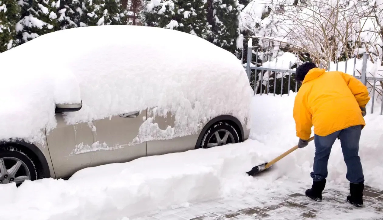 убирают снег возле машины