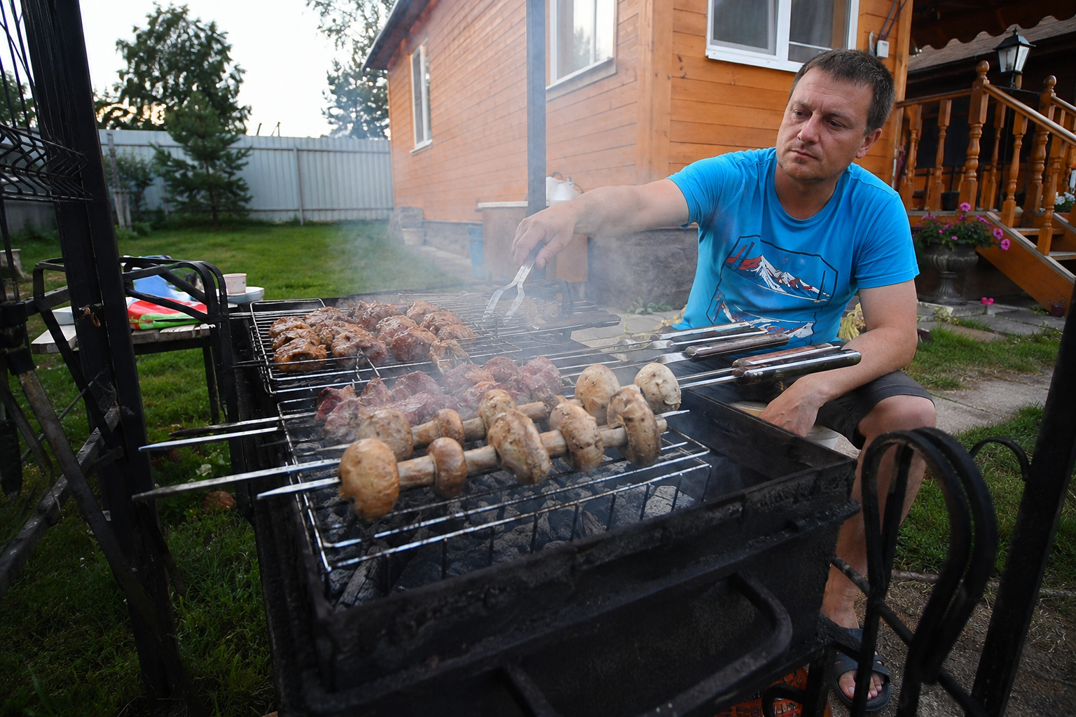 человек жарит шашлыки на даче