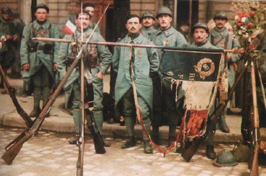 Фотография французских солдат позирующих с разорванным в боях флагом и поднятыми вверх винтовками