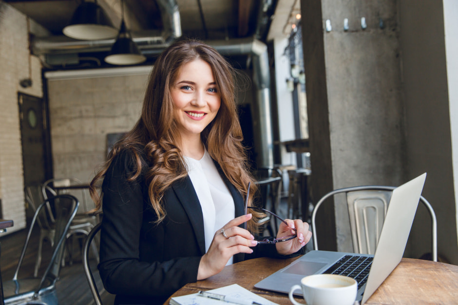 widely-smiling-businesswoman-working-laptop-sitting-cafe.jpg