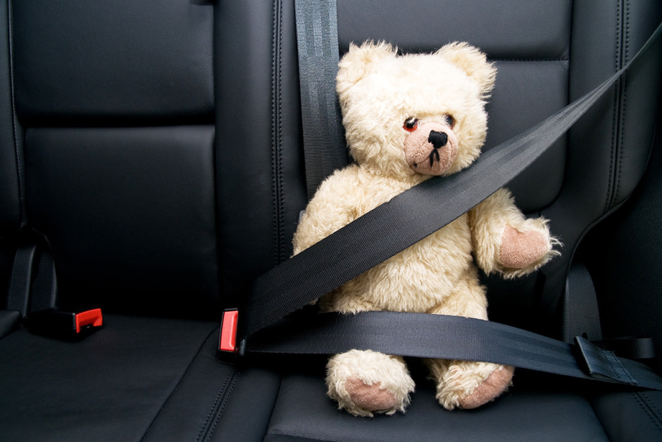 Игрушечный мишка пристегнут в машине